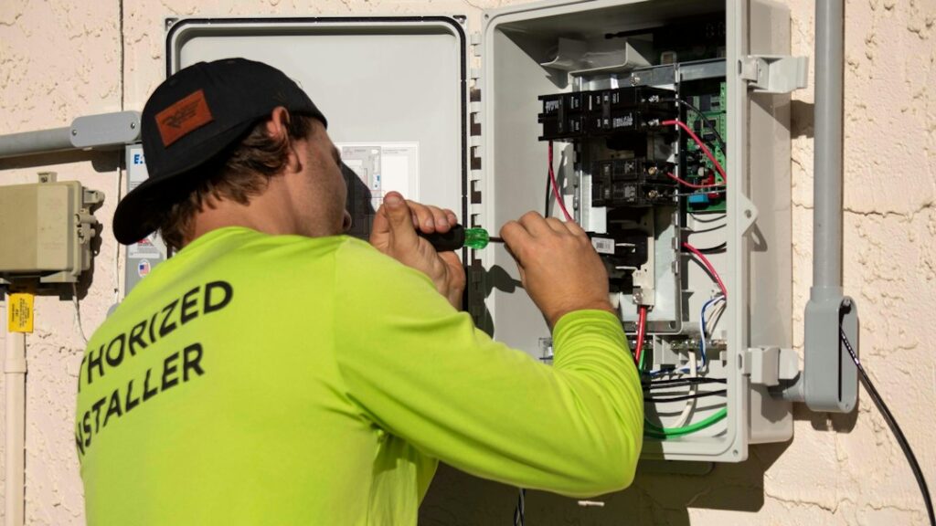 Technician using a screwdriver while troubleshooting an electrical control panel