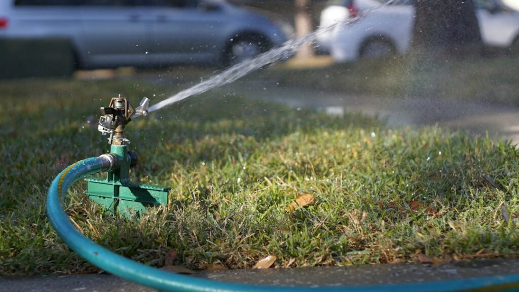 Sprinkler operating on a residential lawn while diagnosing an irrigation valve problem